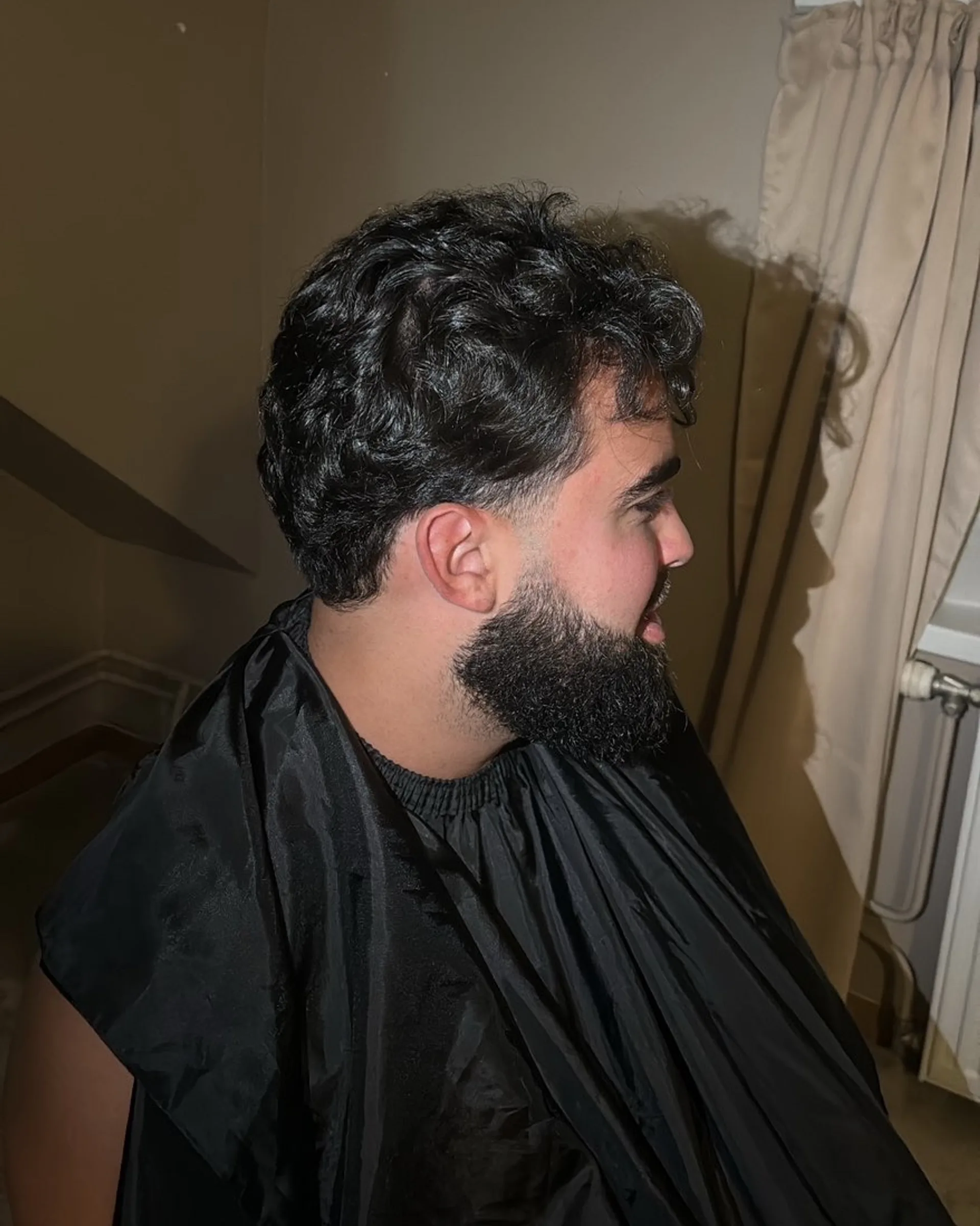 Golvend haar bovenop met een korte zijkant, aansluitend op een strak afgelijnde baard.